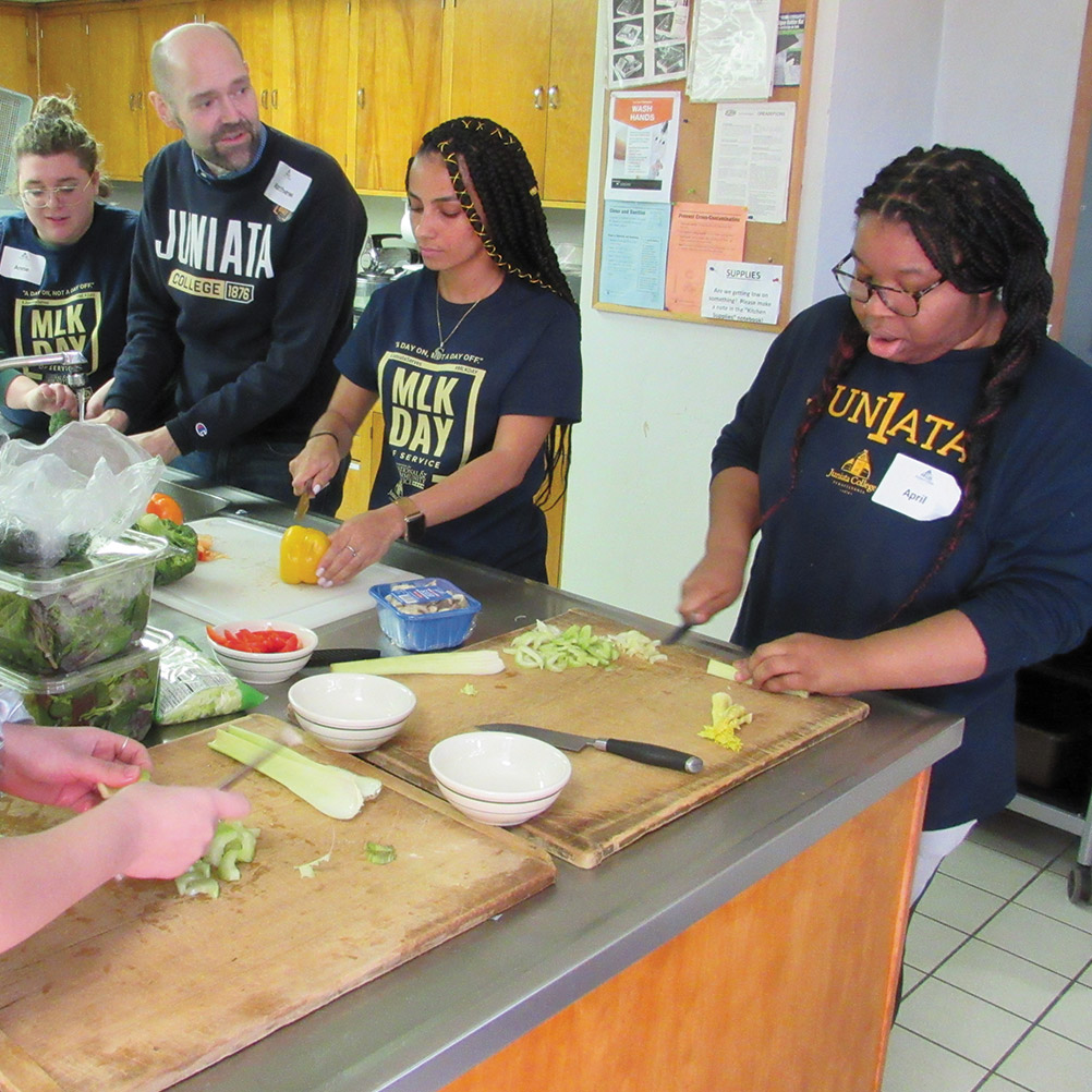 Students and dean of students Mathew Damschroder prepare a community meal
